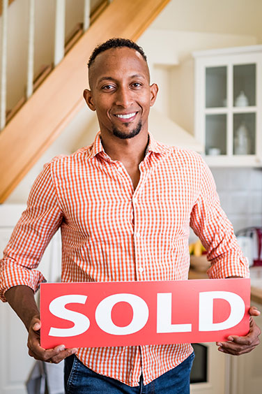 man holding sold sign